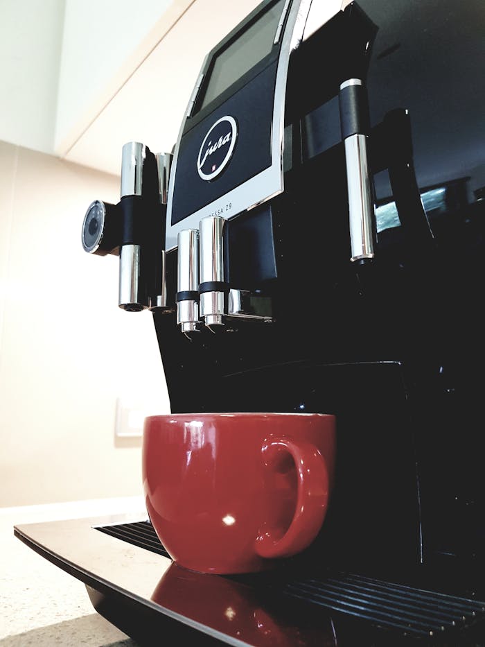 Sleek espresso machine with red coffee cup in bright kitchen setting, ideal for modern cafes.